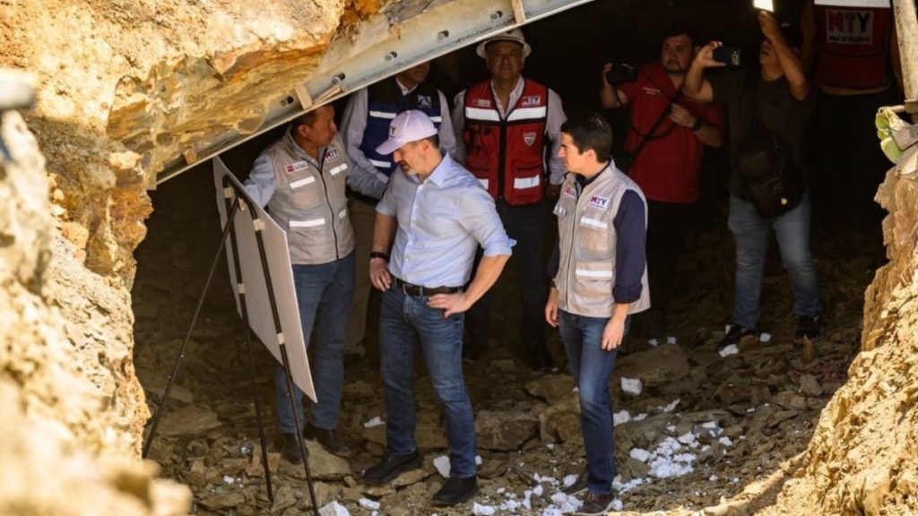 Rescue Workers in Reflective Vests Stand in a Rocky Tunnel, a Man in a Blue Shirt Examines a Whiteboard on a Tripod. - Capitanes Regios