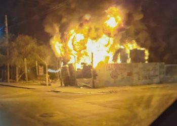 Nighttime Street View of a Building Engulfed in Flames with Thick Smoke Above the Fence. - Capitanes Regios