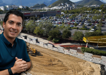 Smiling Man in a Teal Polo Stands at the Edge of a Construction Site Overlooking a Costco Store and a Busy Parking Lot with Hills in the Background. - Capitanes Regios