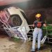 White Suv Crumpled Against a Railing, Tilted over a Drop in a Dimly Lit Underpass; Emergency Responder in Helmet Observes from the Railing Edge. - Capitanes Regios