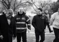 Four Men Walking Outdoors, Smiling and Talking; One Wears a High‑visibility Jacket with Mty Branding (black and White).趙 - Capitanes Regios