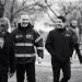 Four Men Walking Outdoors, Smiling and Talking; One Wears a High‑visibility Jacket with Mty Branding (black and White).趙 - Capitanes Regios