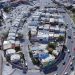Aerial View of a Dense Residential Area with a Circular Road Loop Around a Block of White and Beige Houses. - Capitanes Regios