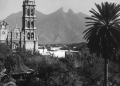 Historic Church with a Tall Bell Tower, Palm Tree in Foreground, and Mountains in the Distance. - Capitanes Regios
