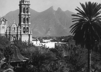 Historic Church with a Tall Bell Tower, Palm Tree in Foreground, and Mountains in the Distance. - Capitanes Regios