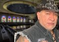 Man Wearing a Studded Black Cowboy Hat and a Sleeveless Denim Vest Stands in a Dilapidated Church with Colorful Stained-glass Windows in the Background. - Capitanes Regios