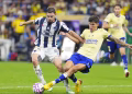 Two Soccer Players in a Blue‑and‑white Striped Kit and a Yellow Kit Fight for the Ball on a Green Field During a Match. - Capitanes Regios