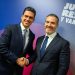 832849169_1631462021675711_2938688054000285643_n - Capitanes Regios Two Men in Dark Suits Shake Hands and Smile at a Formal Event, with a Blue-pink Backdrop and Bold White Text Behind Them. - Capitanes Regios