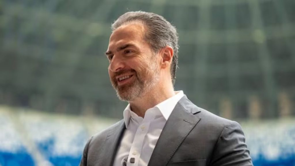 Man in a Gray Suit Smiling Outdoors, Facing Left in a Bright Setting - Capitanes Regios