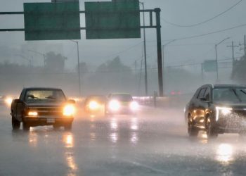 Cars Ride Through a Flooded Highway in Heavy Rain, Headlights on and Spray Obscuring Visibility. - Capitanes Regios