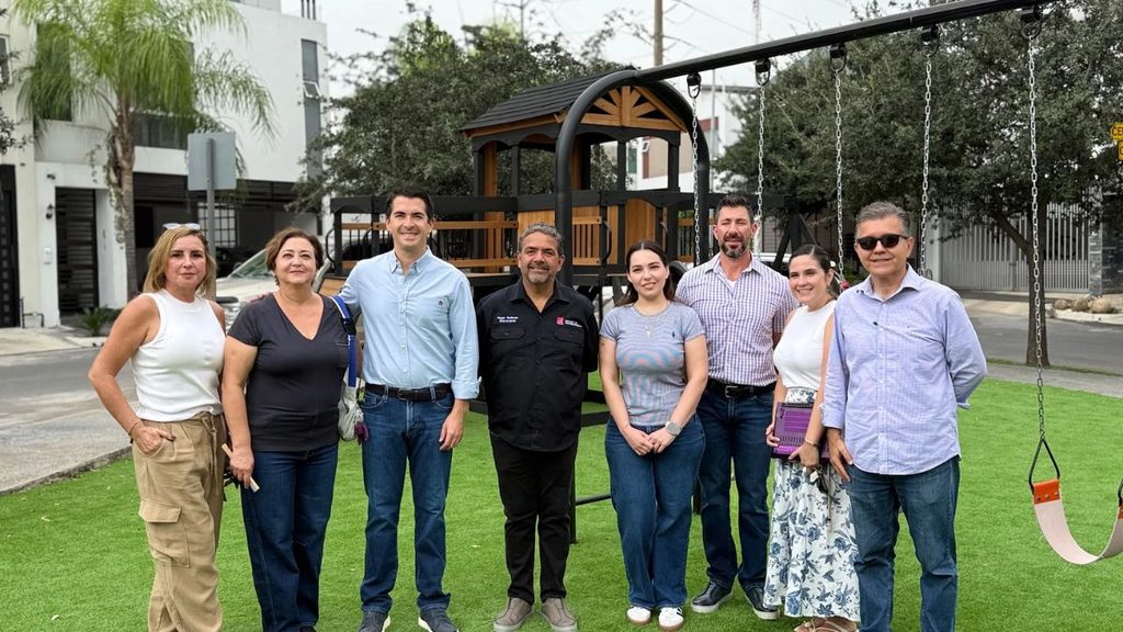 Group of Eight Adults Standing Together on a Synthetic Turf Playground with Swings and a Wooden Play Structure in the Background, Posing for a Photo. - Capitanes Regios